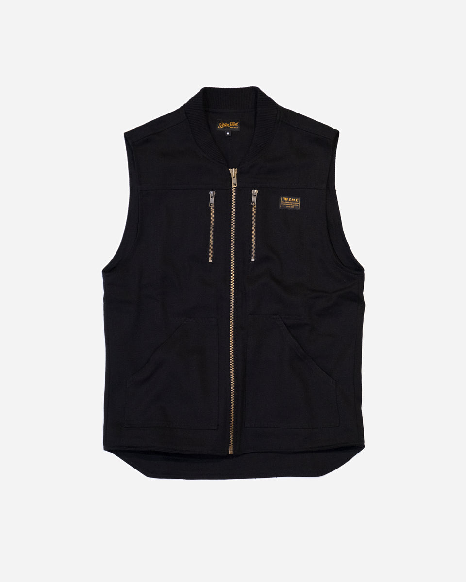 Black motorcycle vest with gold zippers and a Bike Shed Moto Co Logo on a white background